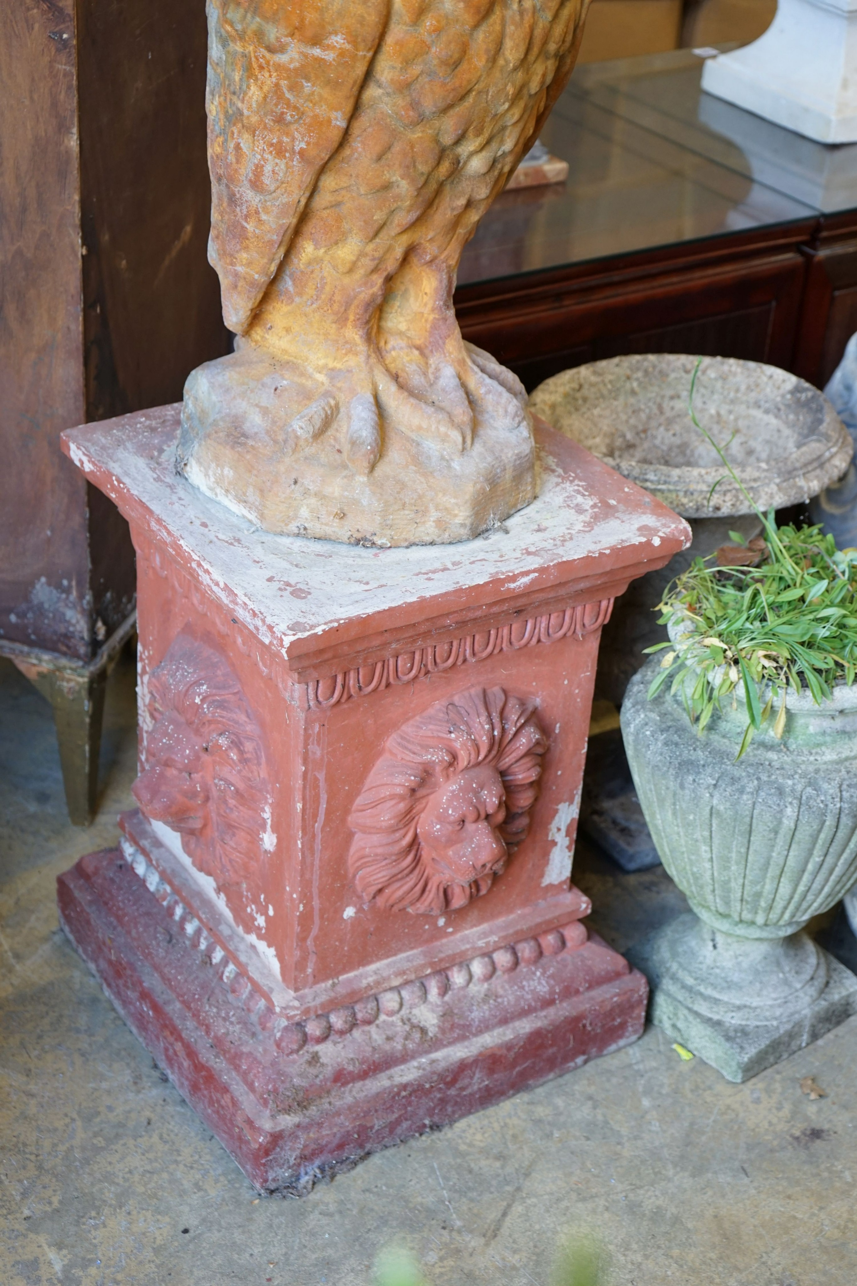 A reconstituted stone owl garden ornament on terracotta plinth, total height 130cm